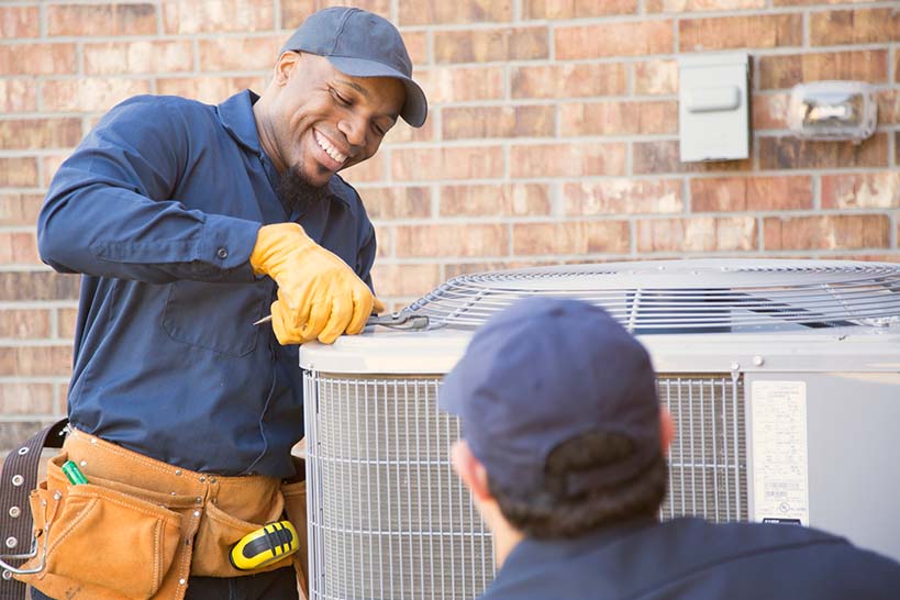 Smiling HVAC Technician repairing an AC unit.