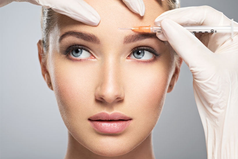 Woman getting a medical cosmetic injection of botox in her forehead.